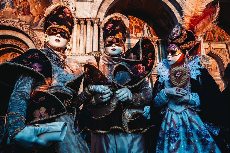 a group of people wearing masks and fancy period clothing
